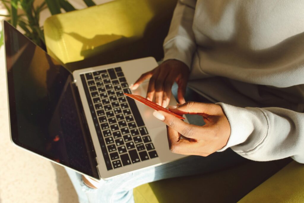 A Person Using a Laptop Holding a Credit Card